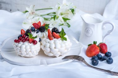 Hassas beyaz meringues plaka üzerinde taze çilek ile. Tatlı Pavlova. Beyaz arka plan. Şenlikli bir düğün pastası.