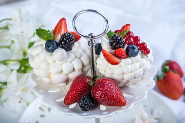 Hassas beyaz meringues plaka üzerinde taze çilek ile. Tatlı Pavlova. Beyaz arka plan. Şenlikli bir düğün pastası.