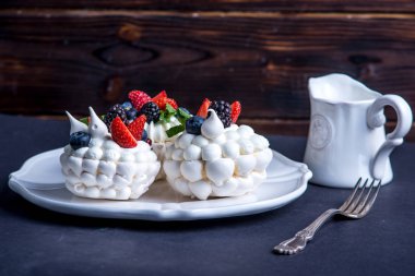 Hassas beyaz meringues plaka üzerinde taze çilek ile. Tatlı Pavlova yakın çekim. Koyu arka plan. Şenlikli bir düğün pastası.