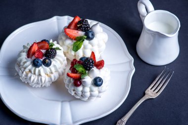Hassas beyaz meringues plaka üzerinde taze çilek ile. Tatlı Pavlova yakın çekim. Koyu arka plan. Şenlikli bir düğün pastası.