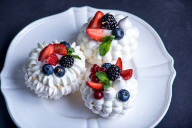 Hassas beyaz meringues plaka üzerinde taze çilek ile. Tatlı Pavlova yakın çekim. Koyu arka plan. Şenlikli bir düğün pastası.