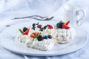 Hassas beyaz meringues plaka üzerinde taze çilek ile. Tatlı Pavlova yakın çekim. Beyaz arka plan. Şenlikli bir düğün pastası.