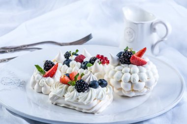 Hassas beyaz meringues plaka üzerinde taze çilek ile. Tatlı Pavlova yakın çekim. Beyaz arka plan. Şenlikli bir düğün pastası.