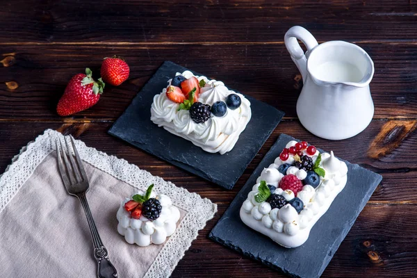 Hassas beyaz meringues plaka üzerinde taze çilek ile. Tatlı Pavlova. Koyu arka plan. Şenlikli bir düğün pastası.