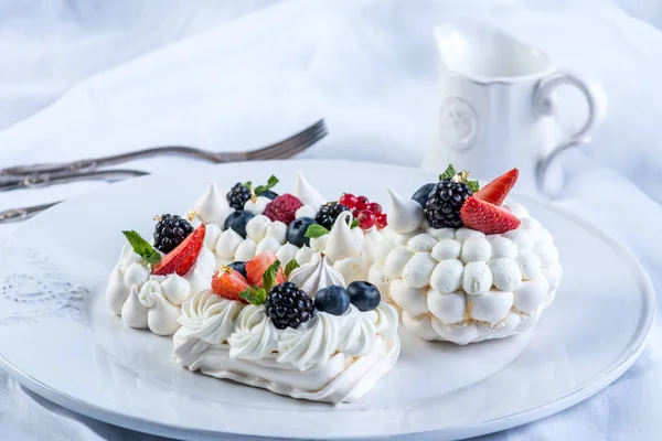 Hassas beyaz meringues plaka üzerinde taze çilek ile. Tatlı Pavlova yakın çekim. Beyaz arka plan. Şenlikli bir düğün pastası.