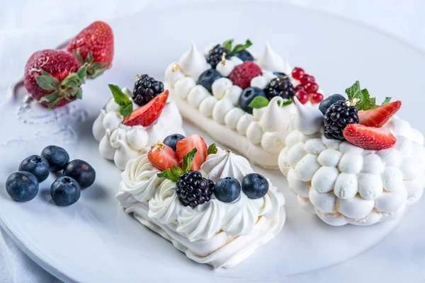 皿の上の新鮮な果実と繊細な白いメレンゲ デザートのパブロバのクローズ アップ 白い背景 結婚式のお祝いケーキ — ストック写真