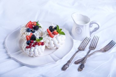 Hassas beyaz meringues plaka üzerinde taze çilek ile. Tatlı Pavlova. Beyaz arka plan. Şenlikli bir düğün pastası.