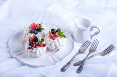 Hassas beyaz meringues plaka üzerinde taze çilek ile. Tatlı Pavlova. Beyaz arka plan. Şenlikli bir düğün pastası.