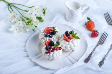 Hassas beyaz meringues plaka üzerinde taze çilek ile. Tatlı Pavlova. Beyaz arka plan. Şenlikli bir düğün pastası.