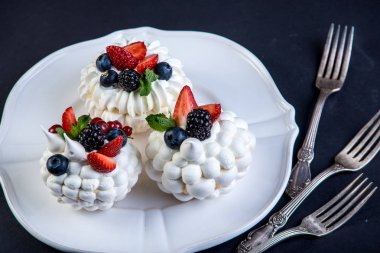 Hassas beyaz meringues plaka üzerinde taze çilek ile. Tatlı Pavlova yakın çekim. Koyu arka plan. Şenlikli bir düğün pastası.