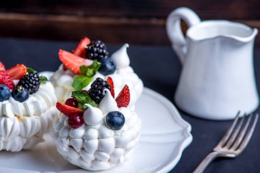 Hassas beyaz meringues plaka üzerinde taze çilek ile. Tatlı Pavlova yakın çekim. Koyu arka plan. Şenlikli bir düğün pastası.