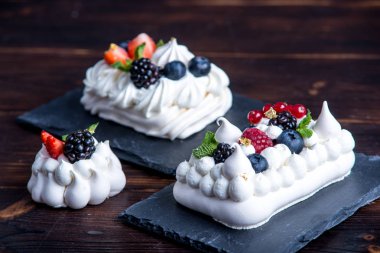 Hassas beyaz meringues plaka üzerinde taze çilek ile. Tatlı Pavlova yakın çekim. Koyu arka plan. Şenlikli bir düğün pastası.