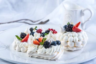 Hassas beyaz meringues plaka üzerinde taze çilek ile. Tatlı Pavlova yakın çekim. Beyaz arka plan. Şenlikli bir düğün pastası.