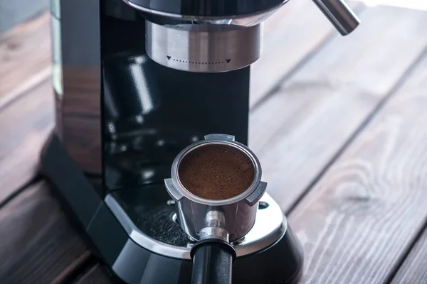 Preparation of espresso. Black coffee machine on the table and a horn with ground grains. Professional coffee brewing at home