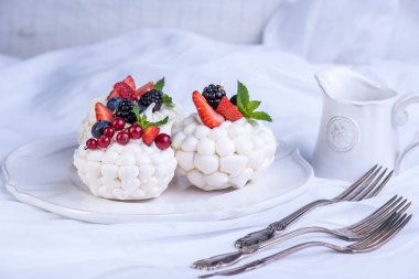 Hassas beyaz meringues plaka üzerinde taze çilek ile. Tatlı Pavlova. Beyaz arka plan. Şenlikli bir düğün pastası.