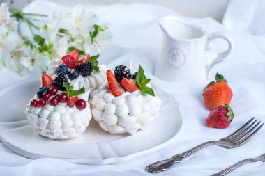 Hassas beyaz meringues plaka üzerinde taze çilek ile. Tatlı Pavlova. Beyaz arka plan. Şenlikli bir düğün pastası.