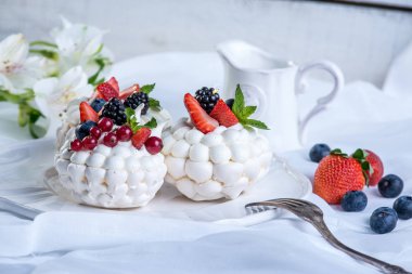 Hassas beyaz meringues plaka üzerinde taze çilek ile. Tatlı Pavlova yakın çekim. Beyaz arka plan. Şenlikli bir düğün pastası.