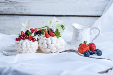 Hassas beyaz meringues plaka üzerinde taze çilek ile. Tatlı Pavlova. Beyaz arka plan. Şenlikli bir düğün pastası.