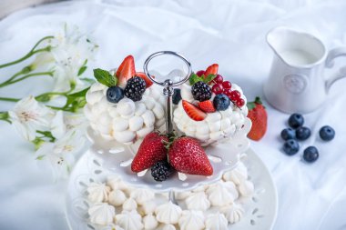 Hassas beyaz meringues plaka üzerinde taze çilek ile. Tatlı Pavlova. Beyaz arka plan. Şenlikli bir düğün pastası.