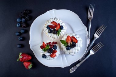 Hassas beyaz meringues plaka üzerinde taze çilek ile. Tatlı Pavlova yakın çekim. Koyu arka plan. Şenlikli bir düğün pastası.