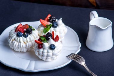 Hassas beyaz meringues plaka üzerinde taze çilek ile. Tatlı Pavlova yakın çekim. Koyu arka plan. Şenlikli bir düğün pastası.