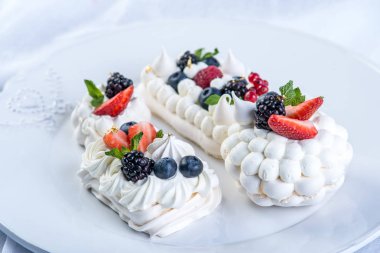 Hassas beyaz meringues plaka üzerinde taze çilek ile. Tatlı Pavlova yakın çekim. Beyaz arka plan. Şenlikli bir düğün pastası.