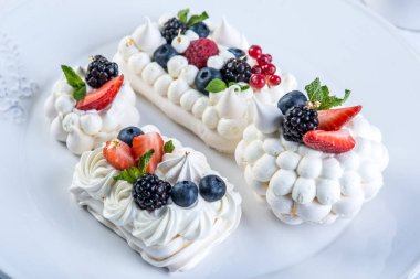 Hassas beyaz meringues plaka üzerinde taze çilek ile. Tatlı Pavlova yakın çekim. Beyaz arka plan. Şenlikli bir düğün pastası.