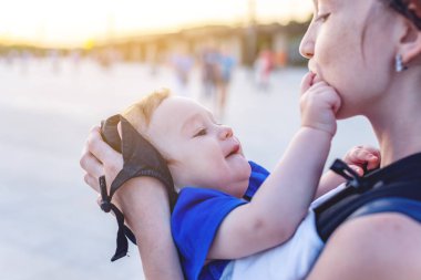 Genç mutlu anne bebek oğlu ile ergo sırt çantası Park'ta yürüyordunuz. Güneşli yaz günü. Modern anne kavramı
