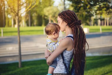 Genç modern mutlu anne ile bebek evlat Sunny Park'ta yürüyordunuz. Sevinç annelik ve Sonbahar ruh kavramı