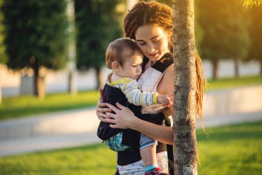 Genç modern mutlu anne ile bebek evlat Sunny Park'ta yürüyordunuz. Sevinç annelik ve Sonbahar ruh kavramı