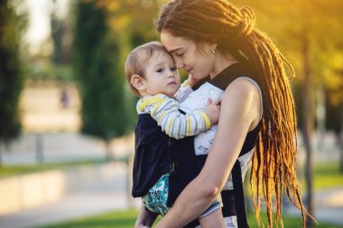 Genç modern mutlu anne ile bebek evlat Sunny Park'ta yürüyordunuz. Sevinç annelik ve Sonbahar ruh kavramı