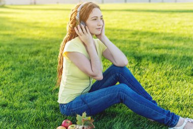 Sonbahar Sunny Park arka plan doğa onun kulaklık ile müzik dinlemek güzel modern kadın. İyi bir ruh hali, favori müzik, mutlu zaman kavramı.