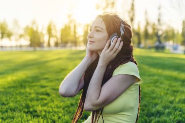 Sonbahar Sunny Park arka plan doğa onun kulaklık ile müzik dinlemek güzel modern kadın. İyi bir ruh hali, favori müzik, mutlu zaman kavramı.