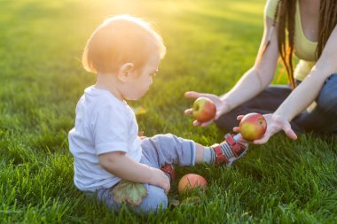 Şirin bebek oğlu bir Sunny parkta elma sayma ile oynarken güzel genç modern anne. Kavram çocuk eğitimi