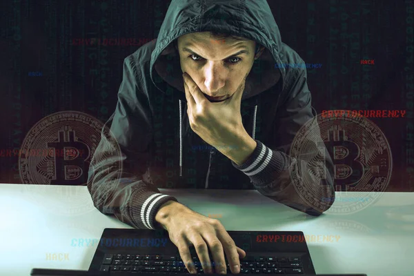 A hacker with a face is trying to steal cryptocurrency using a computer. Scam at Cryptojacking