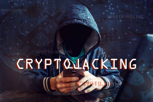 An anonymous hacker without a face is trying to steal cryptocurrency using a computer. Fraud and deception at Cryptojacking