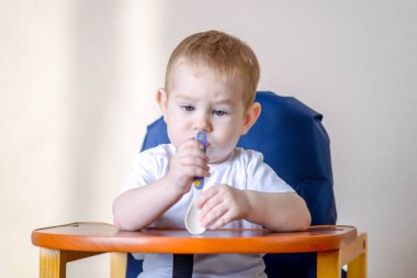 Küçük bir tabak ve kaşık mutfak büyük çocuk masasında yemeye öğrenme oğlu