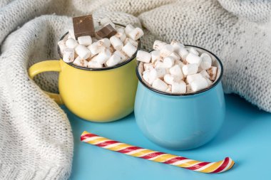 Sıcak çikolata şekerleme top ve çubuk mavi bir arka plan üzerinde bir lolipop kupalar. Sıcak sıcak kış kartı