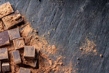 Koyu ahşap zemin üzerine kakao tozu ile karanlık bitter çikolata parçaları. Metin alanı ile kartı