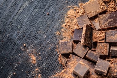 Koyu ahşap zemin üzerine kakao tozu ile karanlık bitter çikolata parçaları. Metin alanı ile kartı