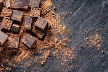 Koyu ahşap zemin üzerine kakao tozu ile karanlık bitter çikolata parçaları. Metin alanı ile kartı