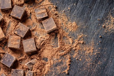 Koyu ahşap zemin üzerine kakao tozu ile karanlık bitter çikolata parçaları. Metin alanı ile kartı