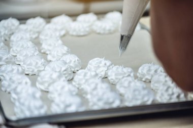 Beze ve tatlılar yapma süreci. Krem eldivenli elini sıkar. Şekerleme üretimi