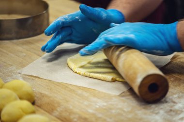 Pasta şefi eldiven kurabiye yapmak için hamur rulo. Şekerleme üretimi kavramı