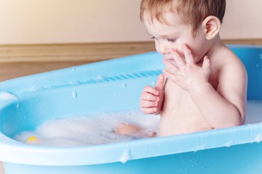 Şirin bebek mavi banyo banyo yıkama. Su ve sabun köpüğü ile oynayan çocuk