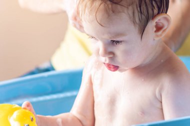 Anne küçük çocuk banyoda mavi bir banyoda yıkama. Hijyen ve su arıtma evde bebekle