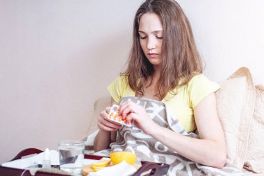 Bir baş ağrısı ve grip termometre ile yatakta kadın ile tabletler ve vitaminler ile tedavi edilir. Kışın mevsimlik soğuk algınlığı