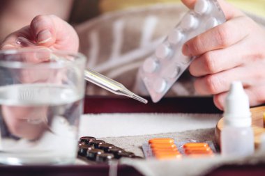 Termometre hapları su ve limon tepsi. Bir soğuk olan bir kişi yatakta tedavi edilir. Soğuk algınlığı, grip ve zamanında tedavi