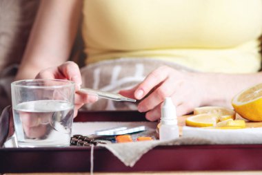 Termometre hapları su ve limon tepsi. Bir soğuk olan bir kişi yatakta tedavi edilir. Soğuk algınlığı, grip ve zamanında tedavi