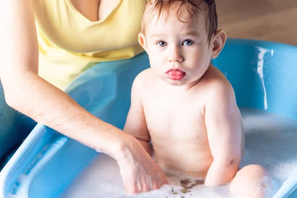青バスで小さな男の子を洗う母 石鹸の泡で入浴です 赤ちゃんと家での衛生と水治療 — ストック写真